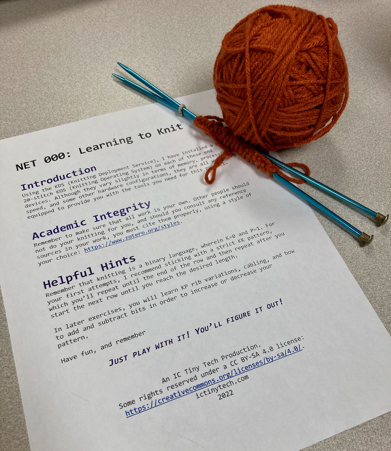 a ball of yarn next to a pair of knitting needles with a small row of stitches cast on--next to them is a handout, the text of which is linked to in the post