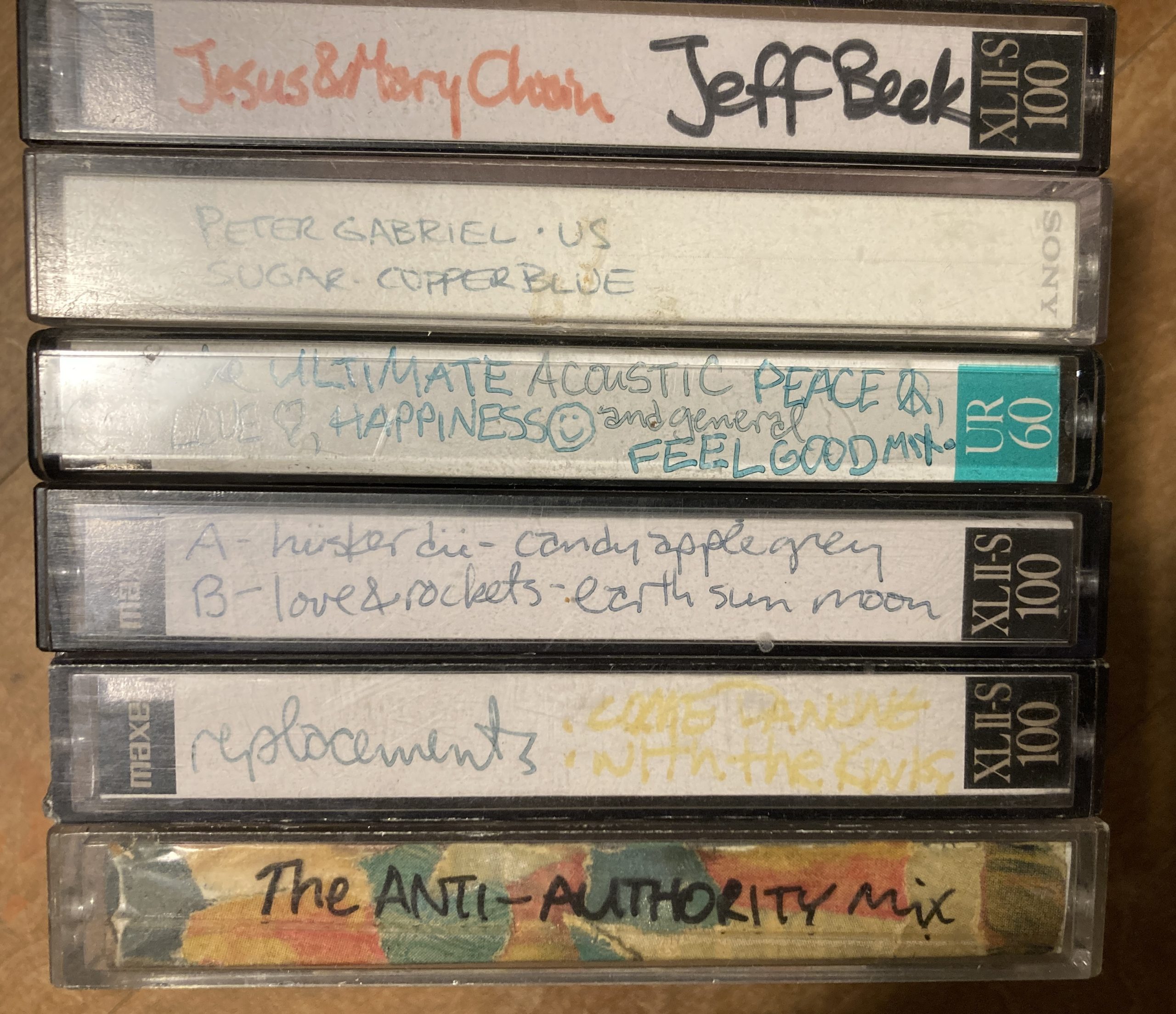 stack of mix tapes including Jesus & Mary Chain/Jeff Beck, Peter Gabriel - Us/Sugar -Copper Blue, The Ultimate ACOUSTIC Peace, Love, and Happiness and General Feel Good Mix, Husker Du/Love and Rockets, Replacements/Kinks, The Anti-Authority Mix